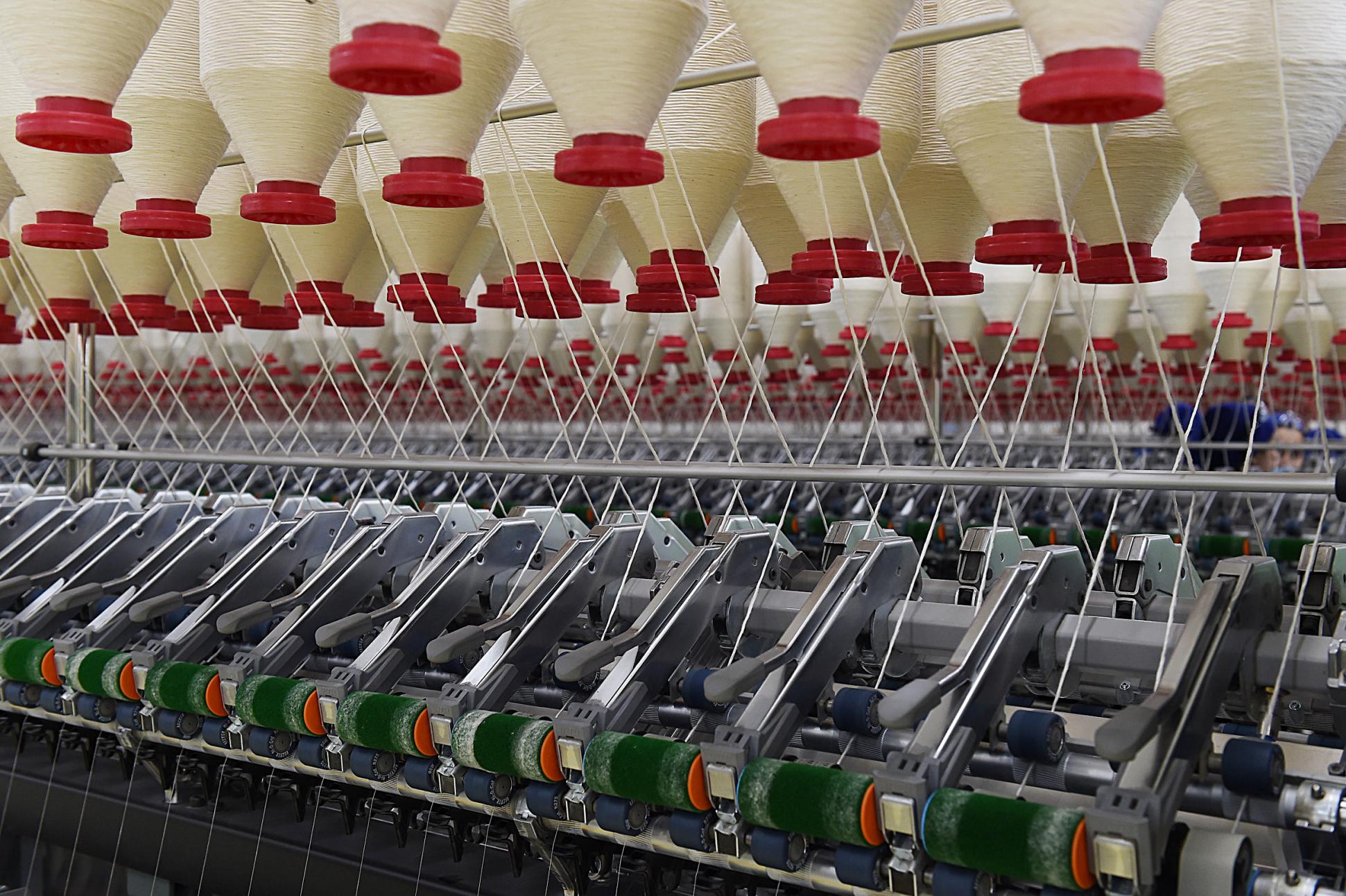 Textile machinery with rows of cotton yarn spools.